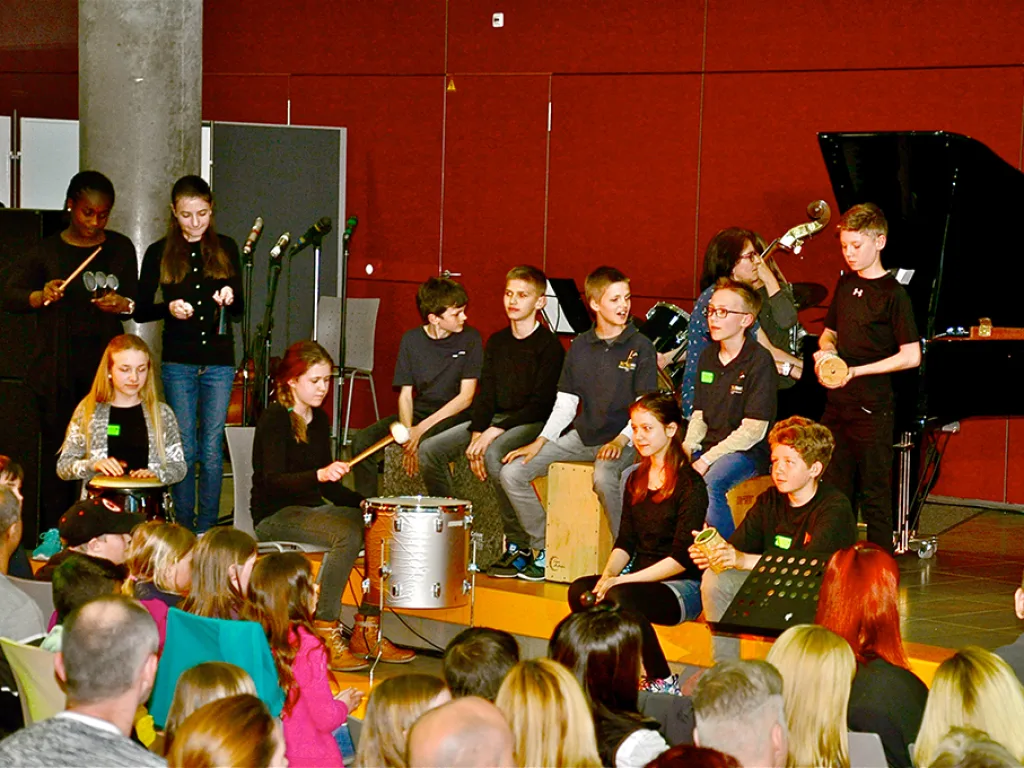 Eine Percussion-Gruppe spielt auf Trommeln neben dem Flügel.
